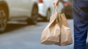 A person holding two brown takeaway bags